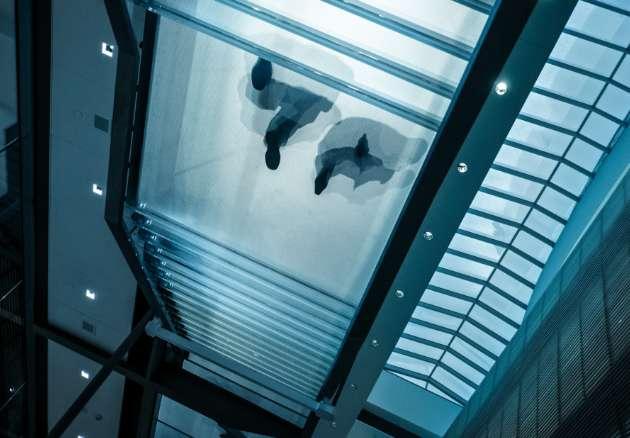 Lower angle view of two people walking on a glass walkway