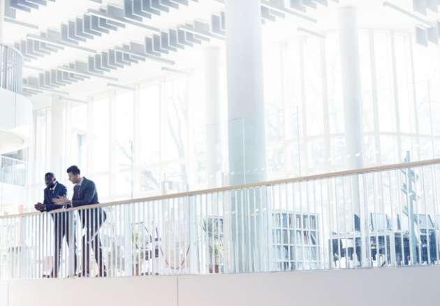 Business people leaning on a railing in an office building