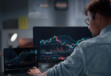 financial professional looking at stock charts on computer screens